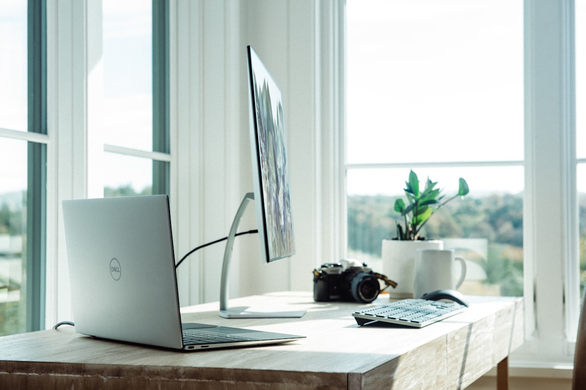 Person working on a laptop at a desk near a window with a rural view